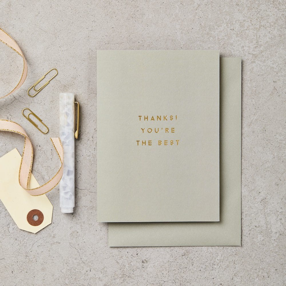 Sage green card with 'THANKS! YOU'RE THE BEST' text on a textured surface with decorative items.