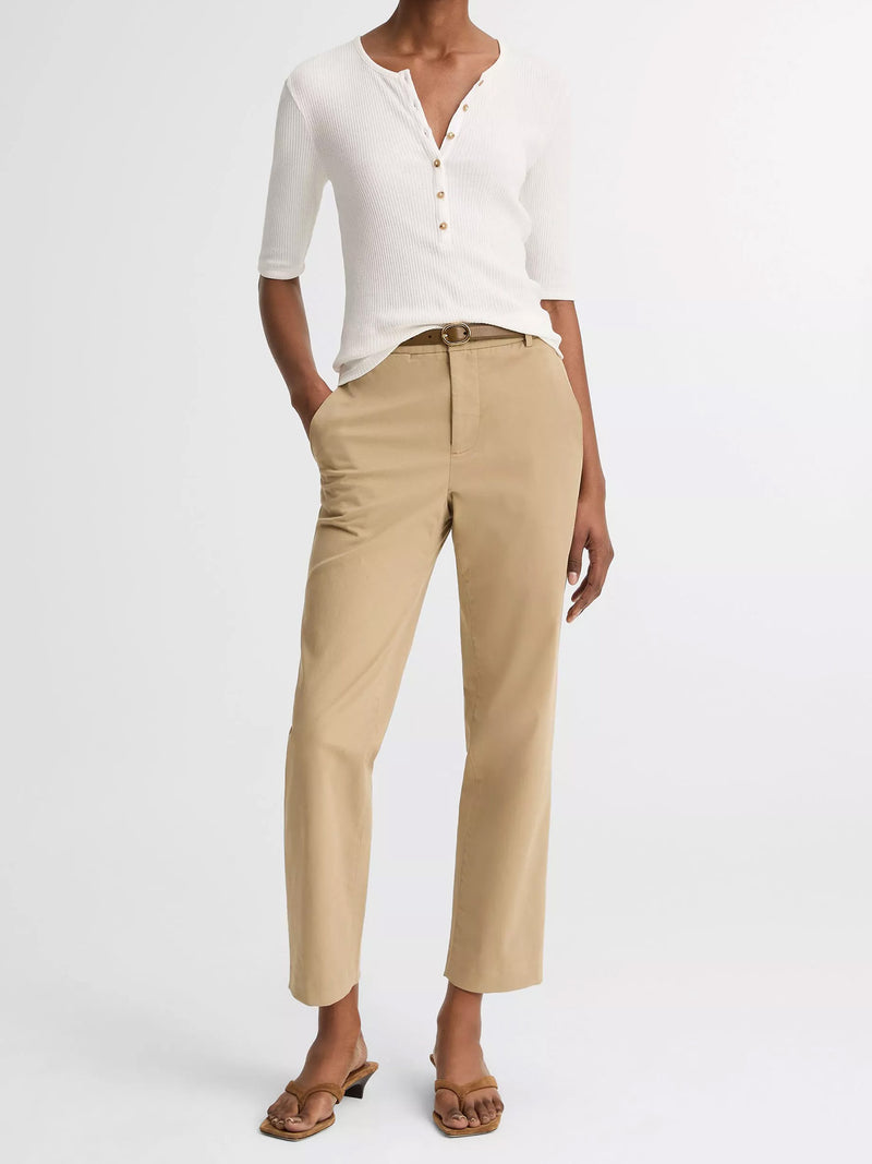 Person wearing a white top and beige pants on a white background
