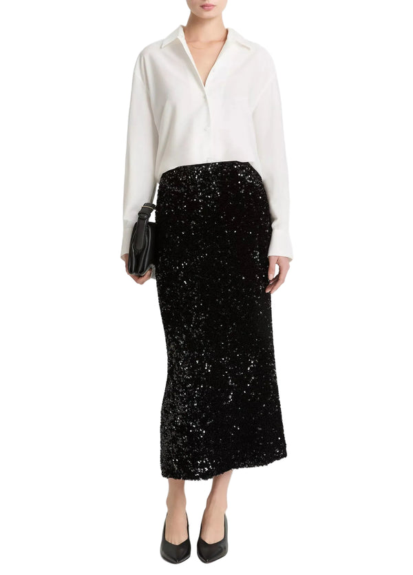 Person wearing a white blouse and black sequin skirt from Vince
