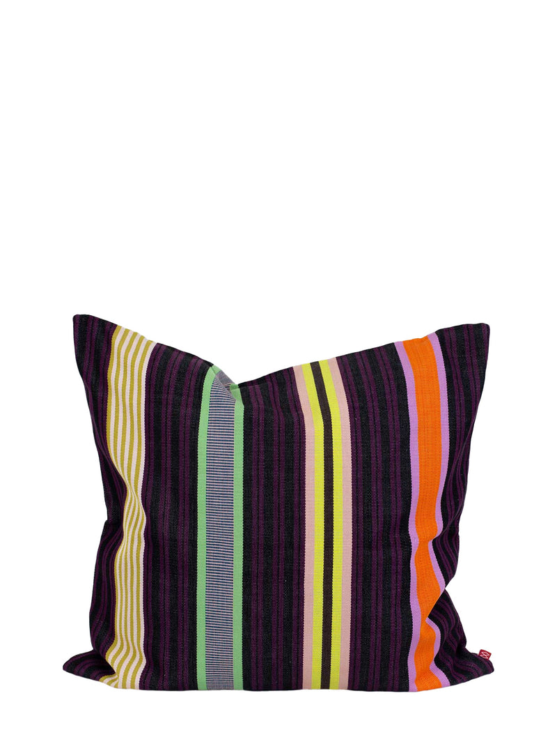 A square throw pillow with a vibrant multicolor striped pattern featuring on base of dark purple and dark wine red, thin and wide stripes in lemon yellow, grass green, olive green, bright orange, magenta, and light soft pink vertical stripes, and a small red brand label on the right seam, shown against a plain white background.