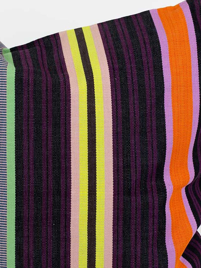 A close-up of a woven canvas textile with vertical stripes in wine red and very dark purple, acid yellow, nude pink, magenta pink, orange, sage green and black mixed with white against a grey studio background.