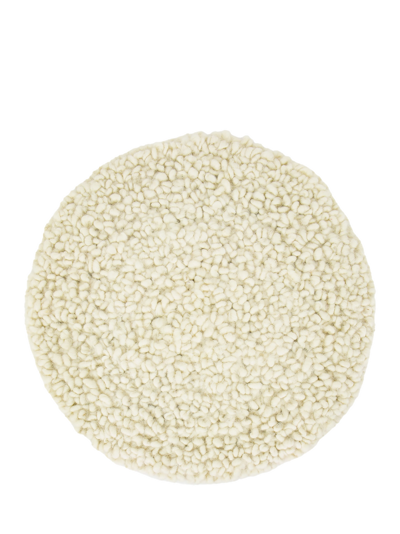 Round natural white seating pad with wool curling on circling pattern photographed on a white background