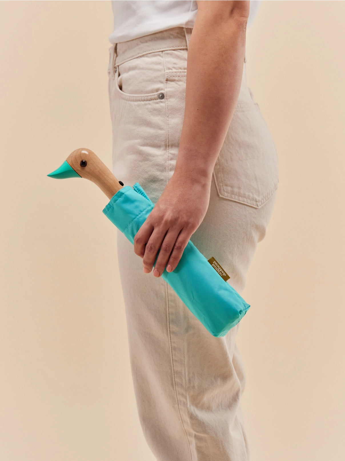 Person holding a mint duck-shaped tool against a beige background