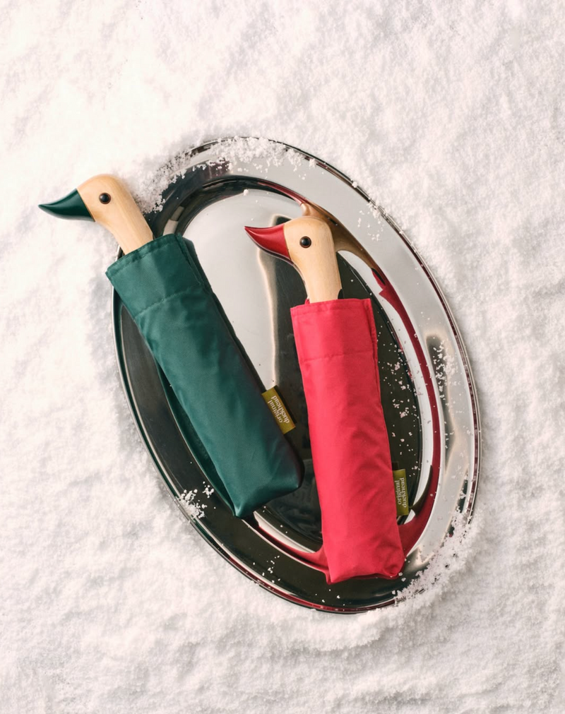 Two folded umbrellas, one green and one red, with duck-shaped handles on a white background.