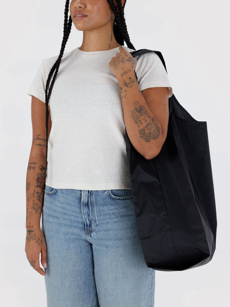 Person wearing a black tote bag over one shoulder on a white background