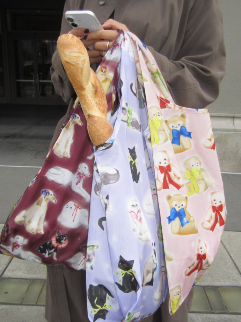 Person holding a bag with teddy bear pattern, another with black cats, and a third with dogs.