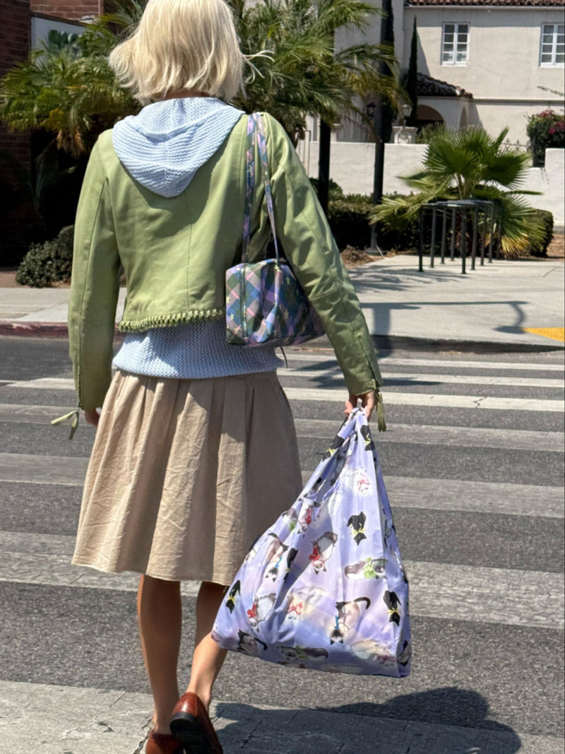 Person crossing a street holding a patterned bag