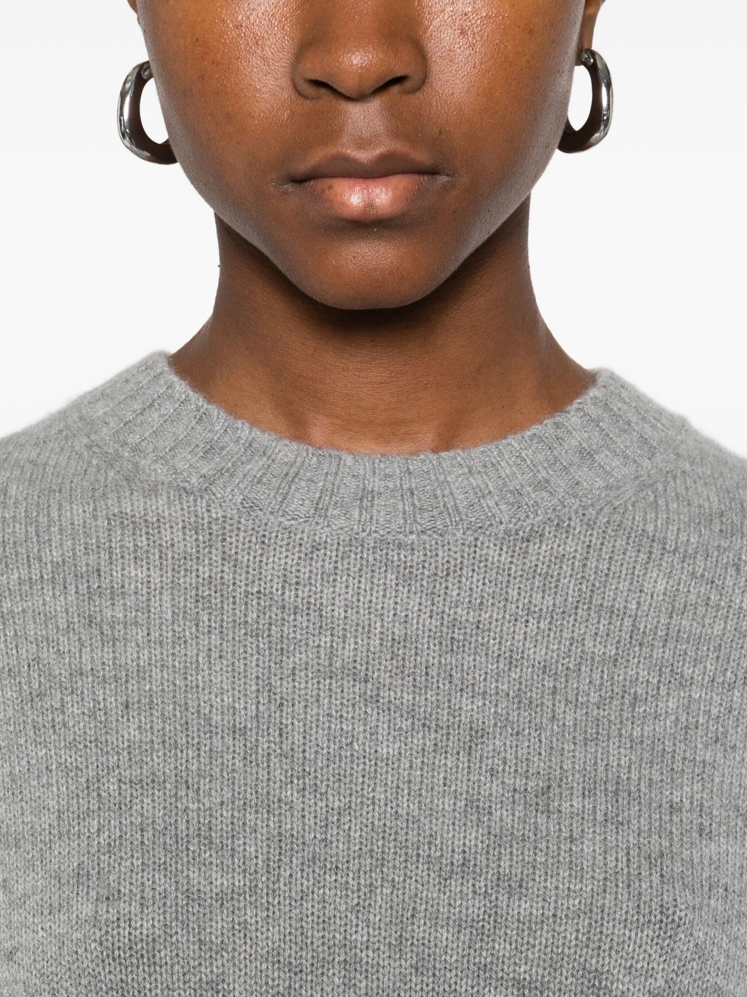 Person wearing a gray sweater with a plain background