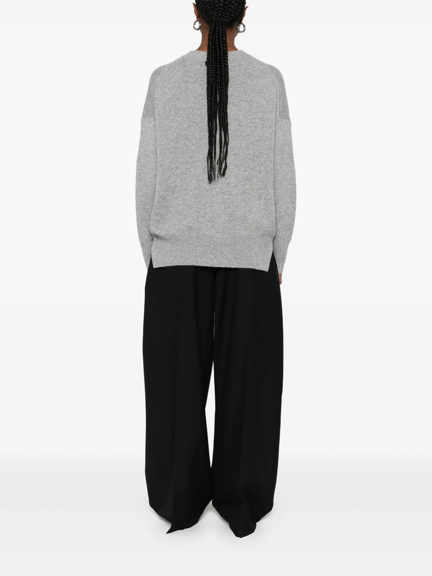 Person wearing a gray sweater and black pants on a white background