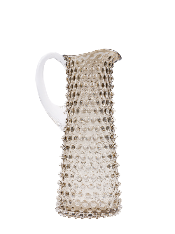 A tall, slender brown glass jug with a classic hobnail pattern, featuring a tapered silhouette and an arched handle.