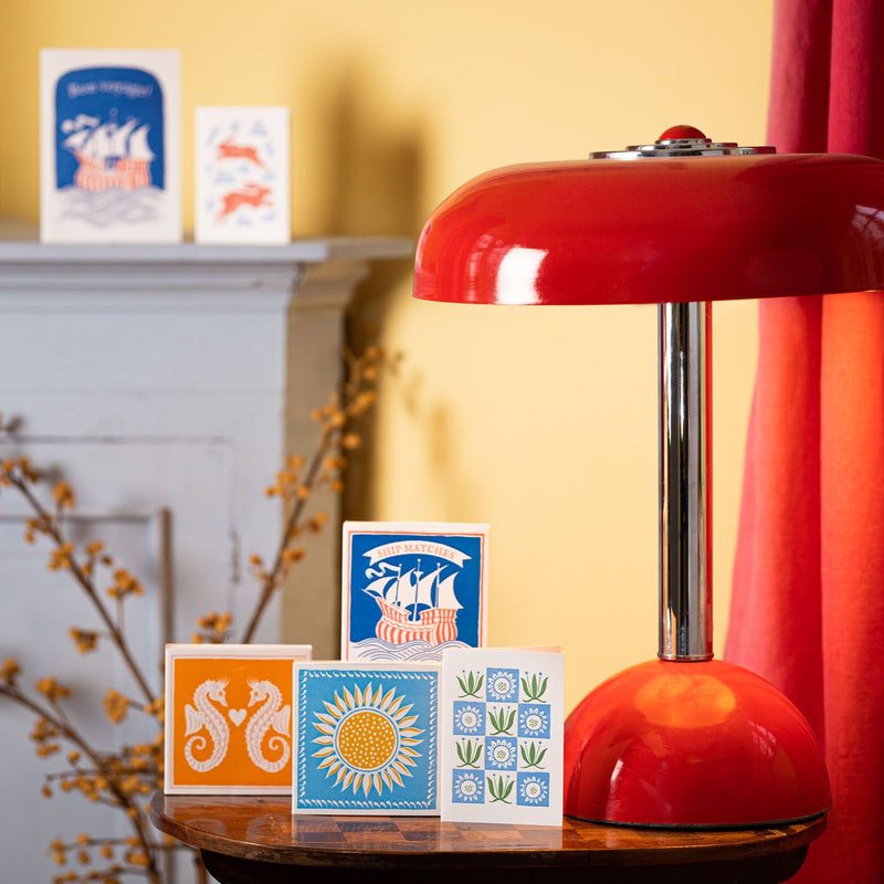 Red lamp on a table with decorative cards and a blurred background