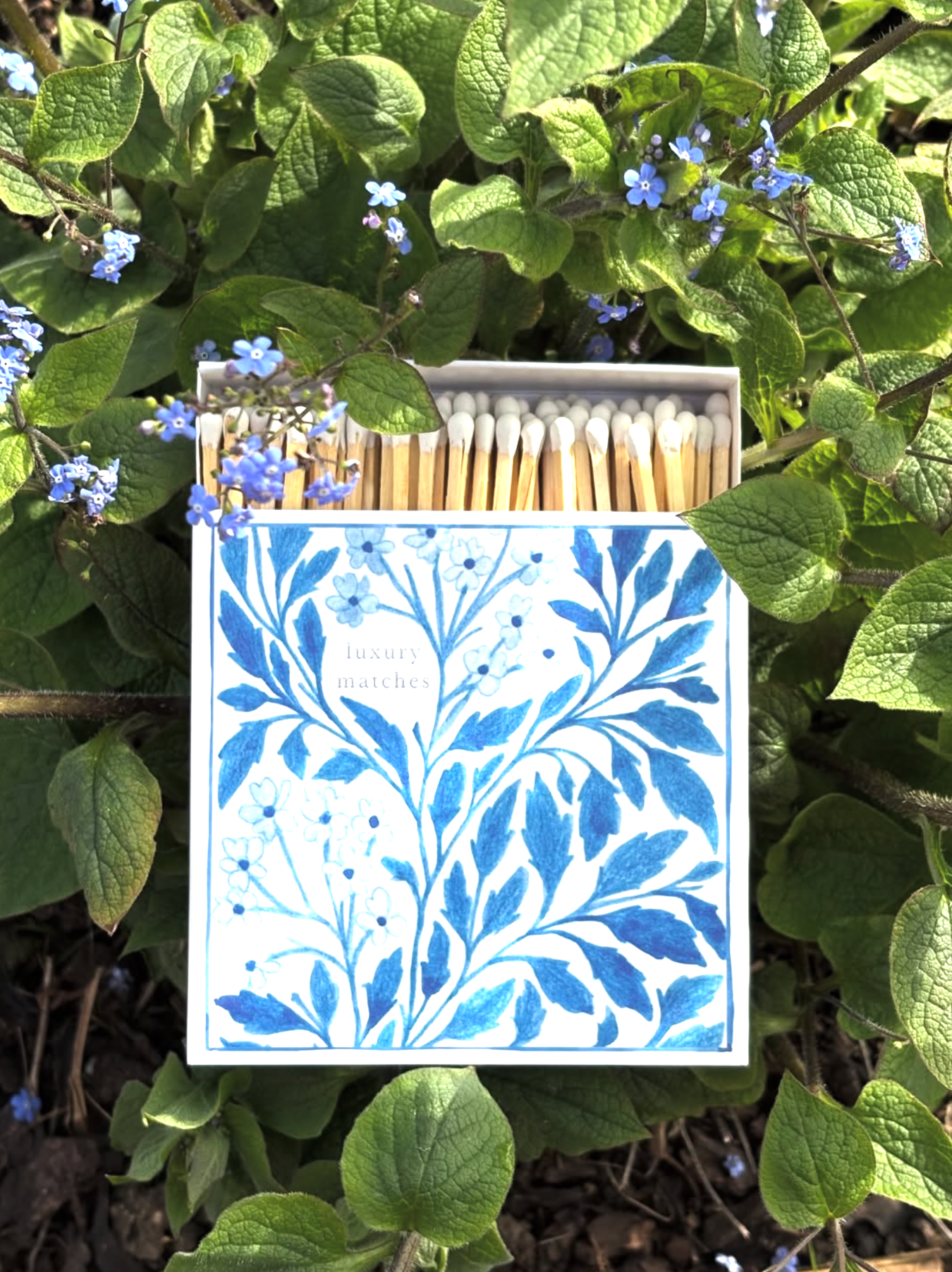 Matches with decorative blue floral design on a white background, surrounded by green leaves.
