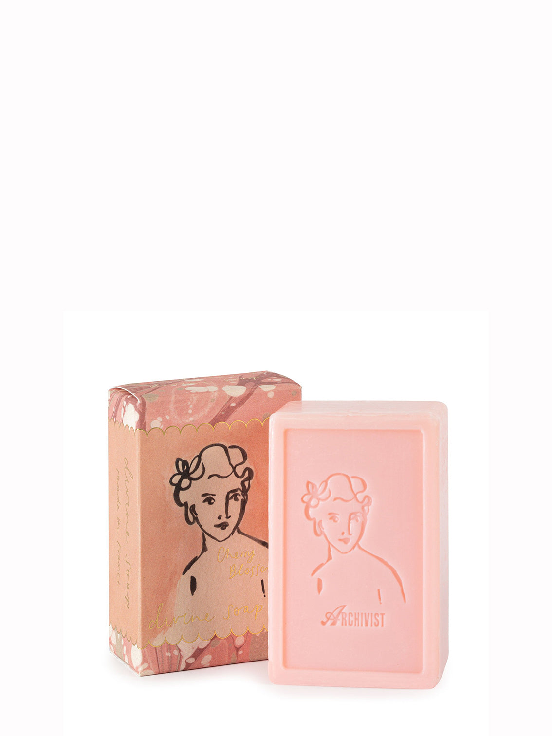 A bar of soap with a pinkish hue next to its packaging, which features a black and white illustration of a woman's face.