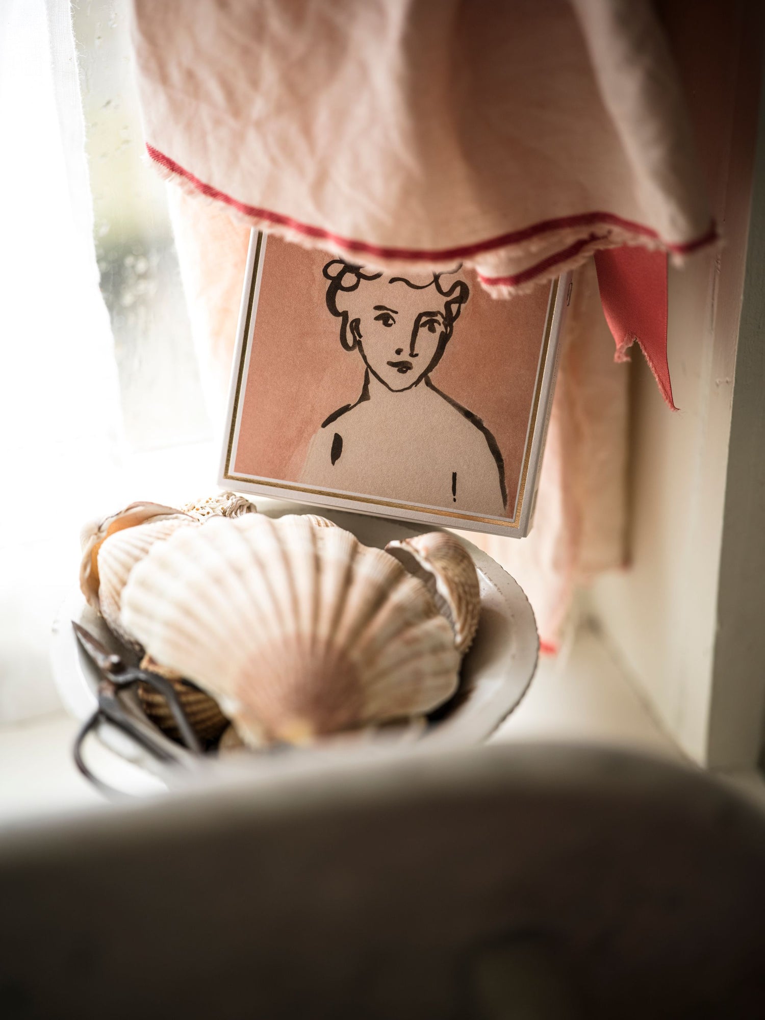 Small framed portrait of a woman with a shell and basket in the foreground