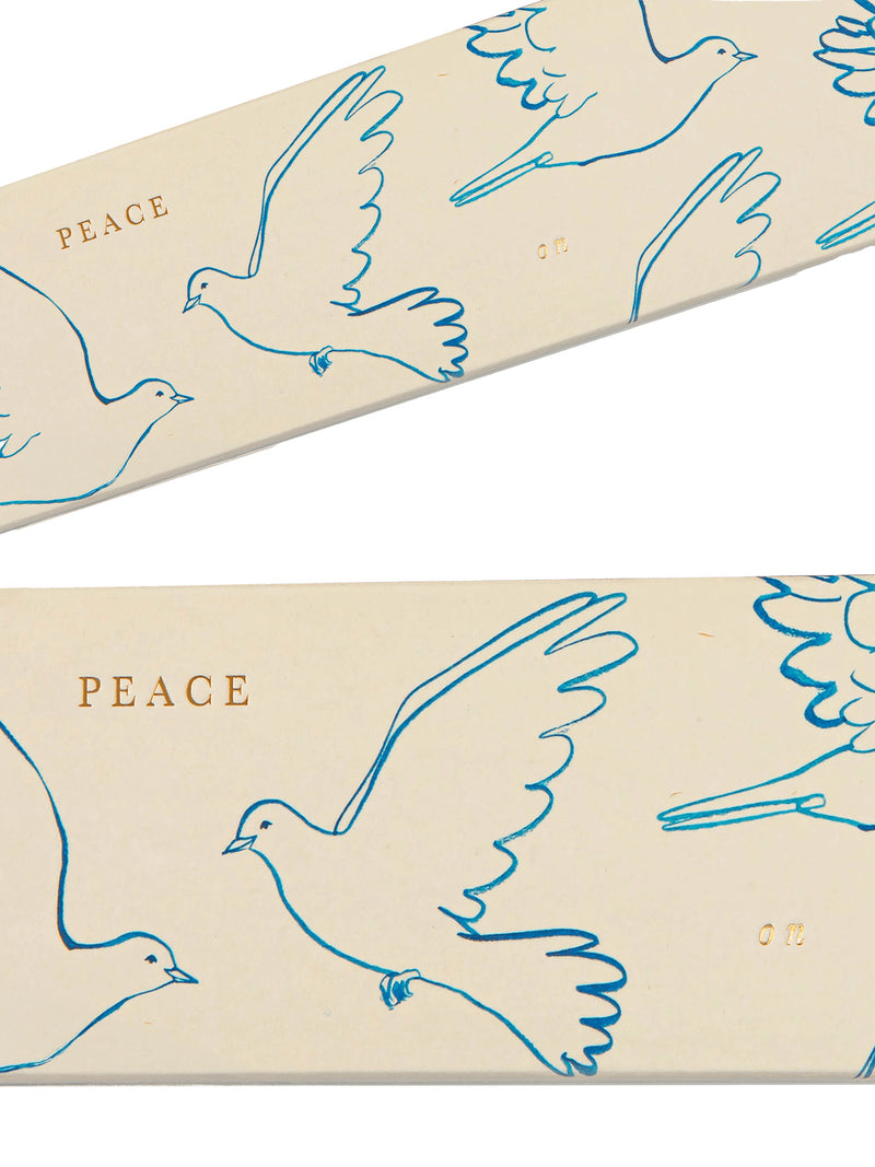 A close-up of a cream-colored product package or box featuring a repeating pattern of blue fluid line drawings of doves with their wings spread in flight and the word 'PEACE on' printed in gold.