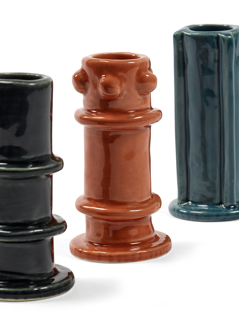 Three ceramic candle holders in black, brown, and blue on a white background