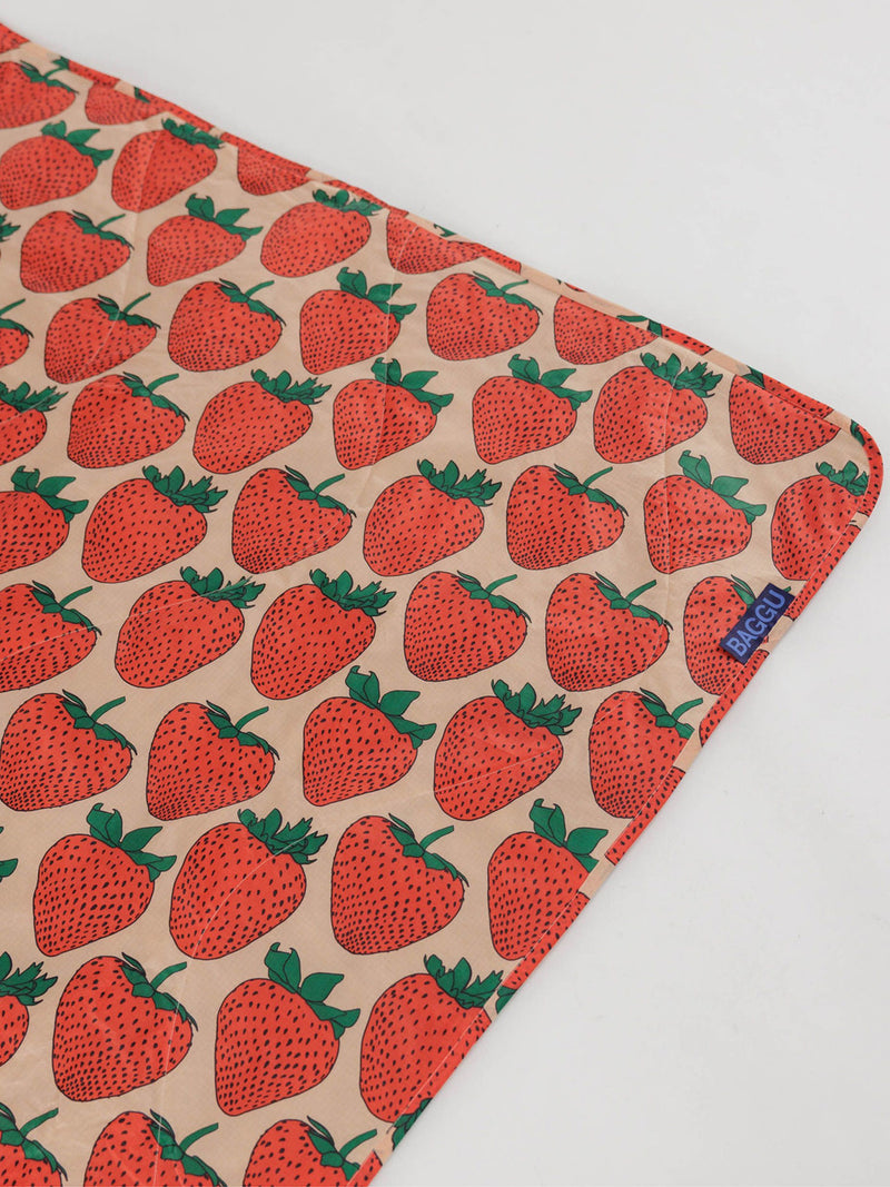Picnic blanket with red strawberry pattern on a beige background