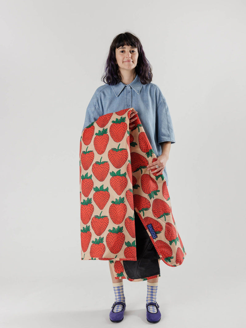 Person holding a long, patterned fabric with strawberry design against a white background