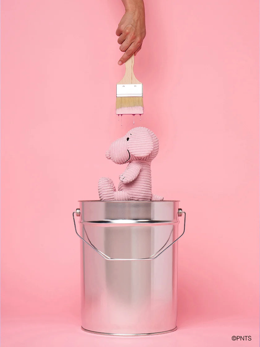 Pink snoopy dog in a metal bucket with a brush on a pink background