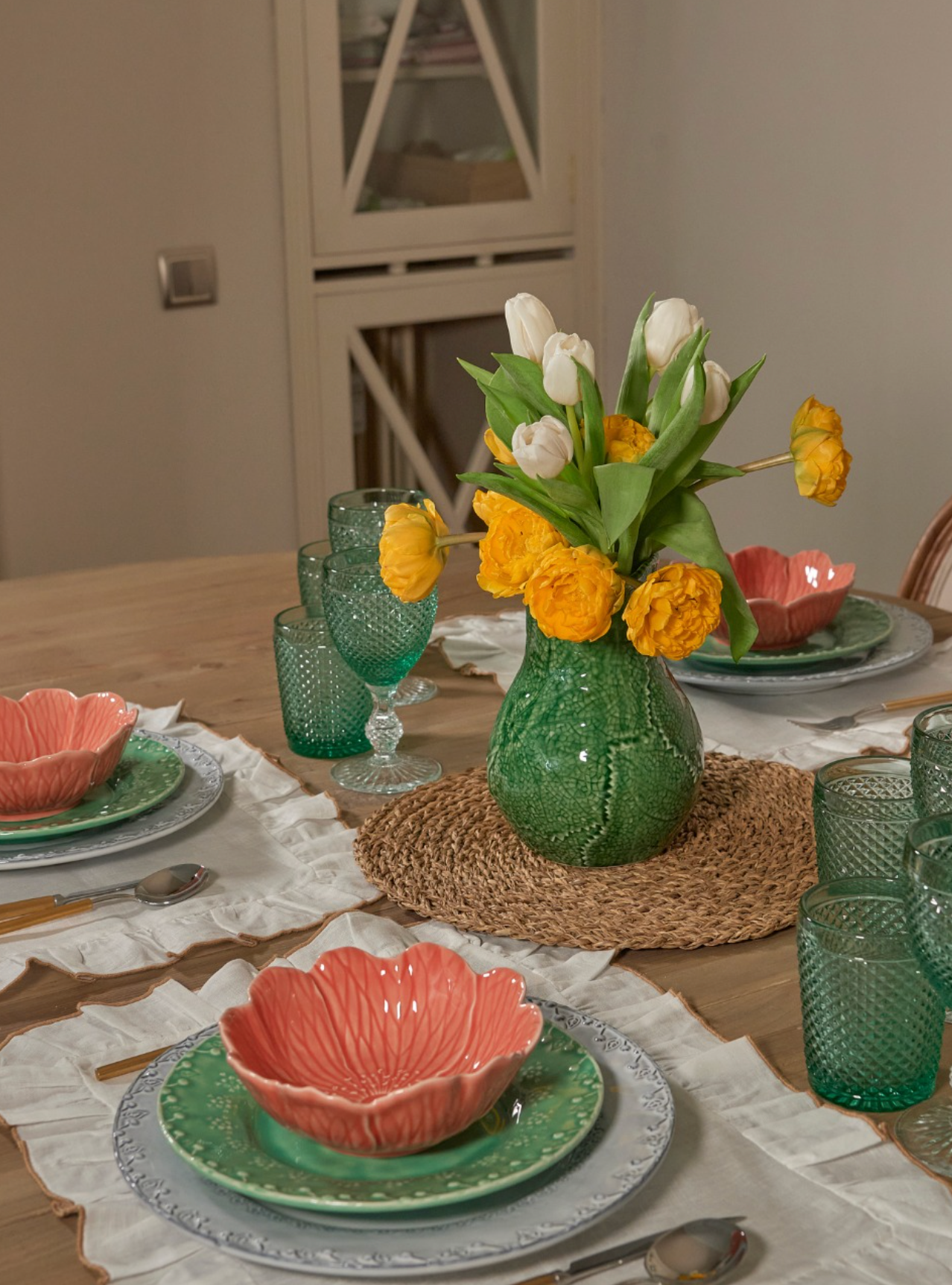 Dining table set with floral centerpiece, plates, and glasses.