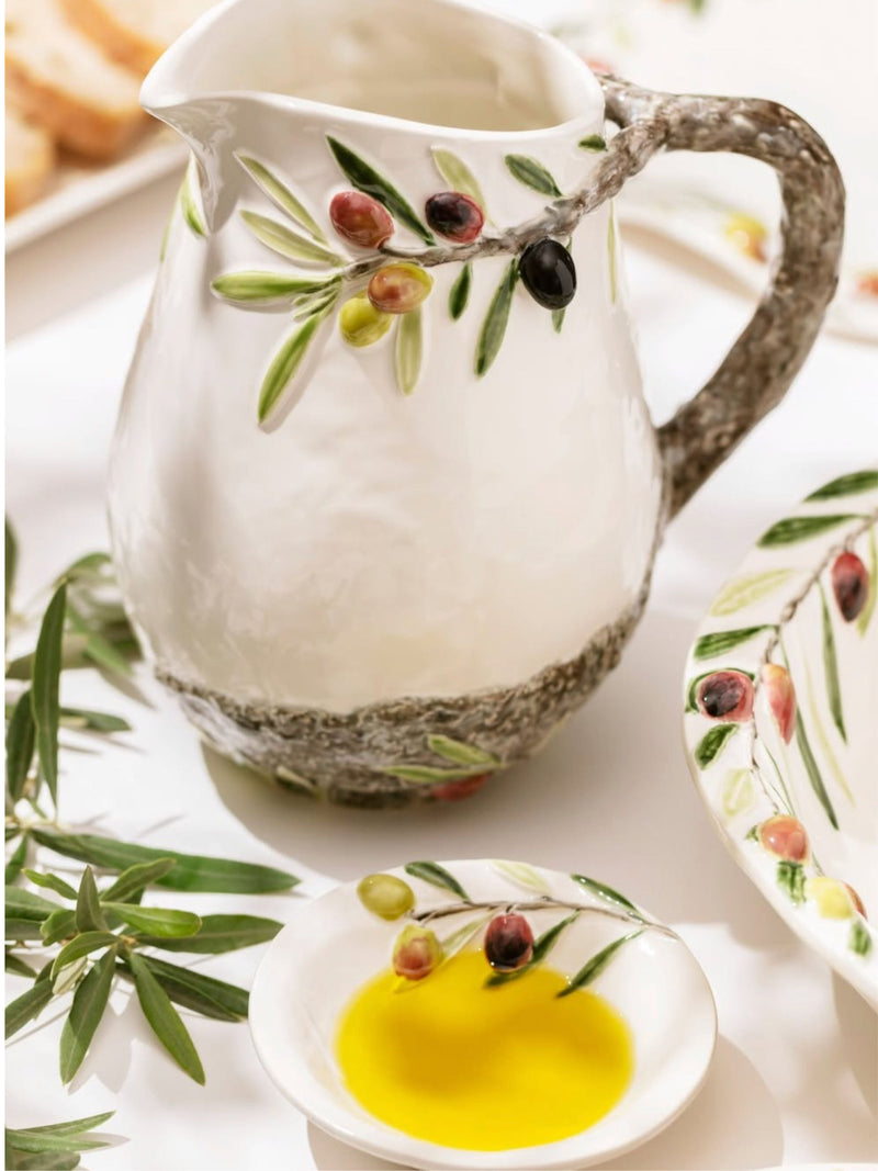 Decorative ceramic pitcher with olive design on a white surface