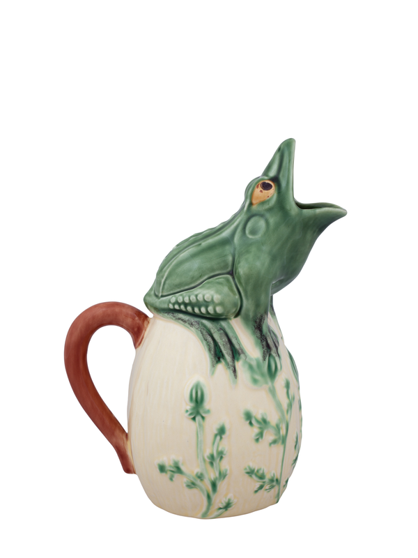 A ceramic pitcher with a green frog design on it, with the frog's mouth open and flippers apart, sitting atop a beige body with green floral accents.