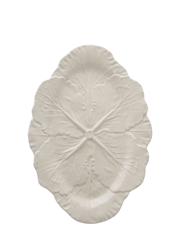 An oval-shaped, ivory-colored ceramic serving platter with a detailed design resembling a cabbage leaf.