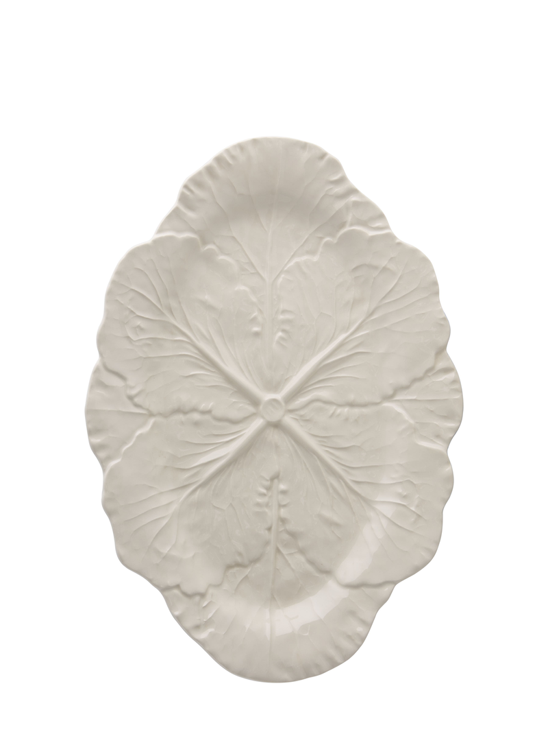 An oval-shaped, ivory-colored ceramic serving platter with a detailed design resembling a cabbage leaf.