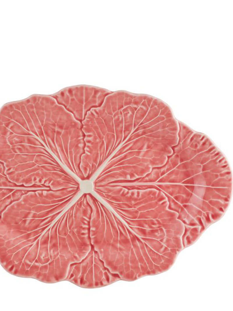 A close-up of an oval ceramic plate with a naturalistic sculpted cabbage design, featuring a textured pinkish-red surface with lighter cream-colored veins radiating from the center, shown on a plain white background.