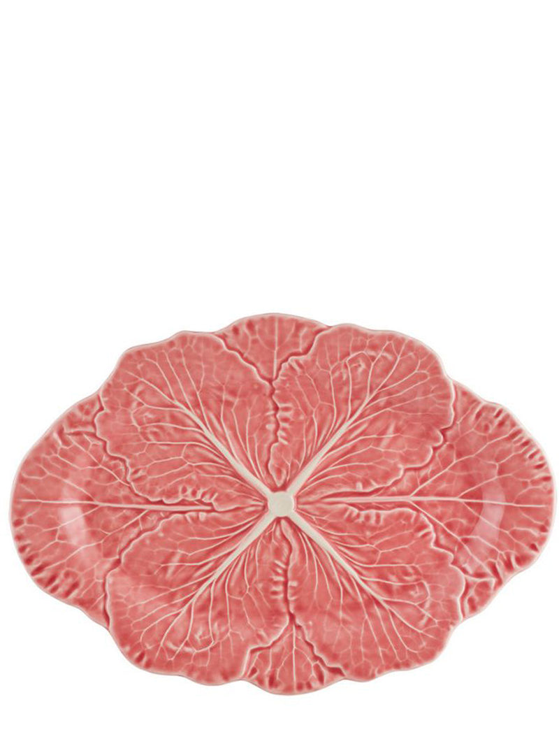 An oval-shaped pink ceramic plate with a detailed cabbage pattern, photographed from directly above on a solid white background.
