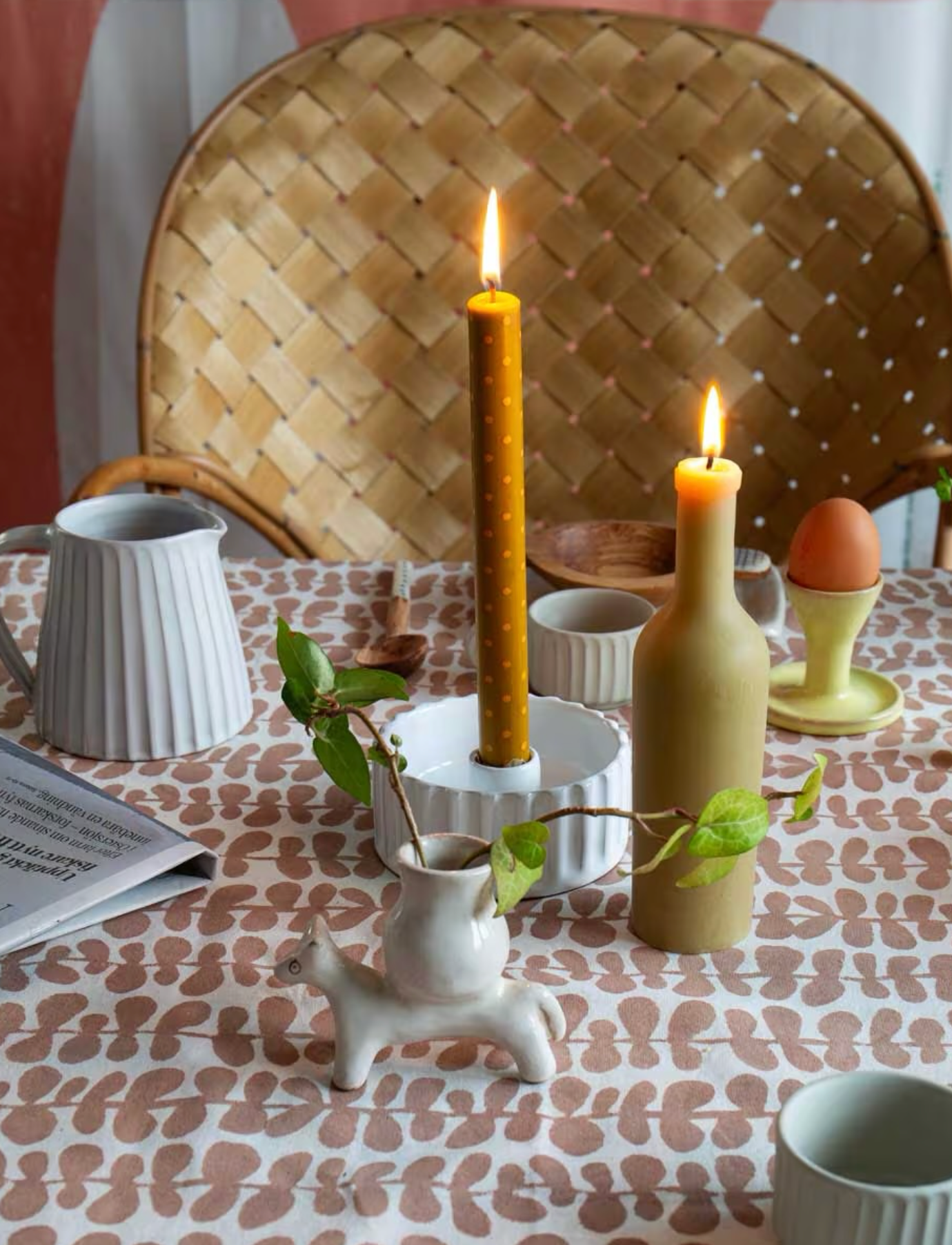 Decorative table setting with candles, vases, and a woven chair.