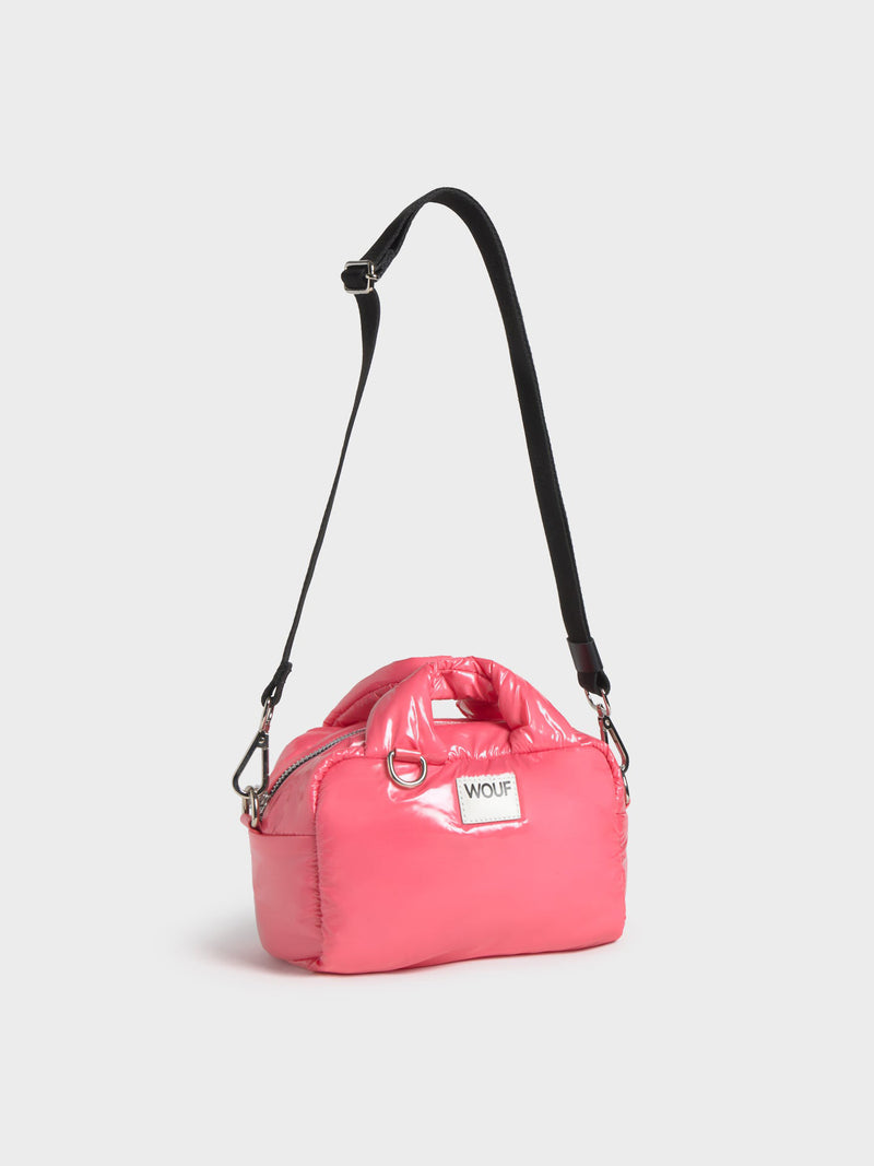 Pink handbag with a black strap on a white background