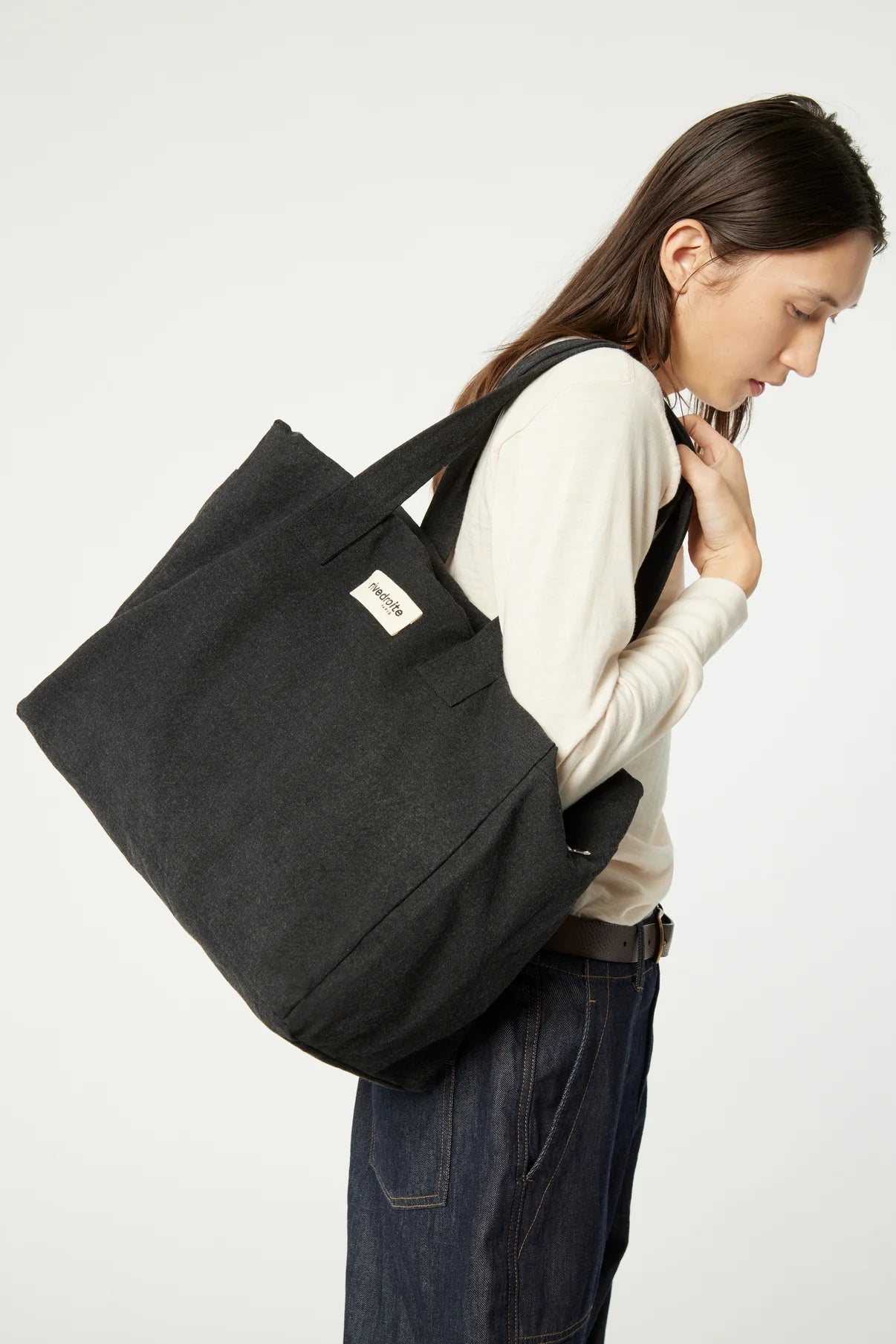 Woman carrying a black tote bag on a white background