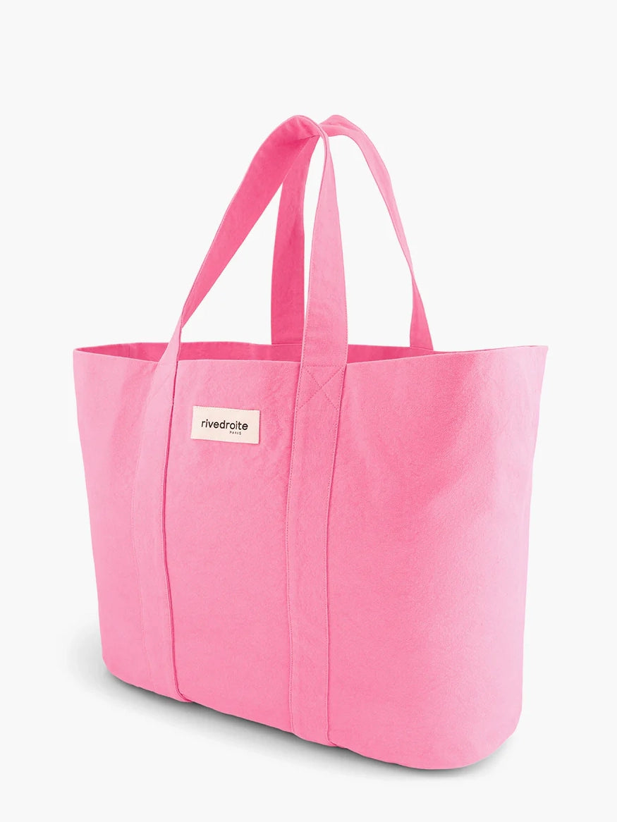 Pink tote bag with a visible brand label on a white background