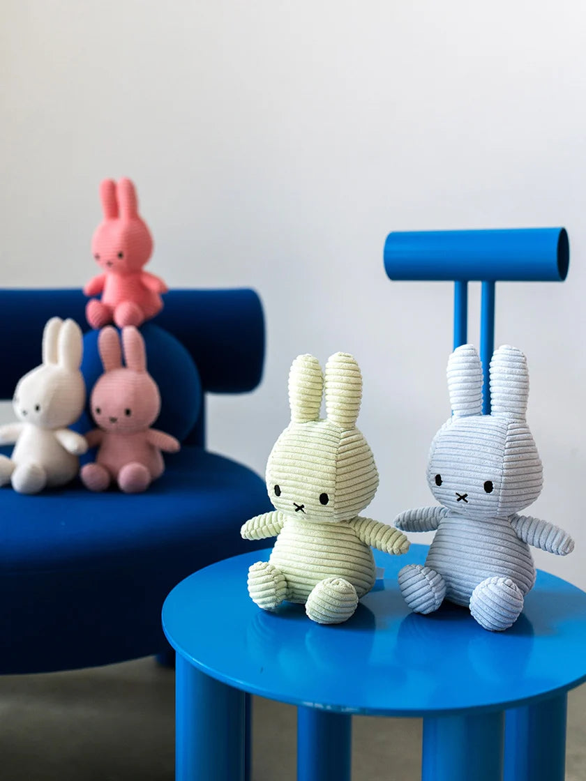 Colorful plush bunny toys on a blue chair and table against a white background