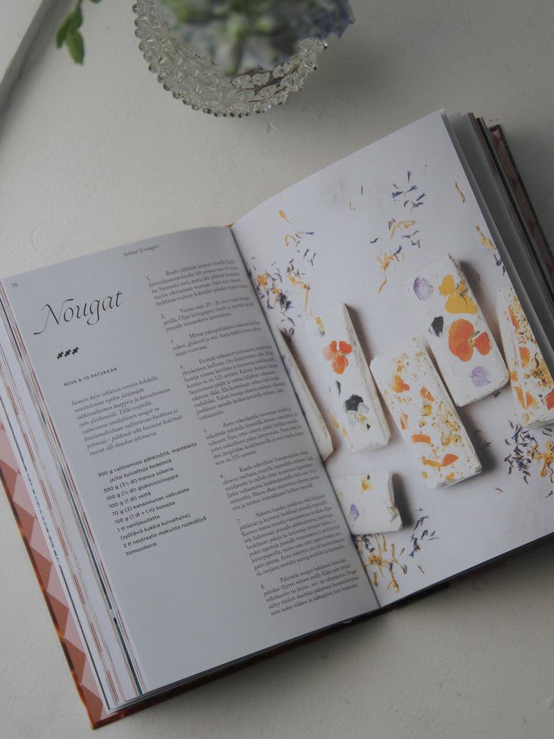 Open book with a page featuring floral designs on a white surface