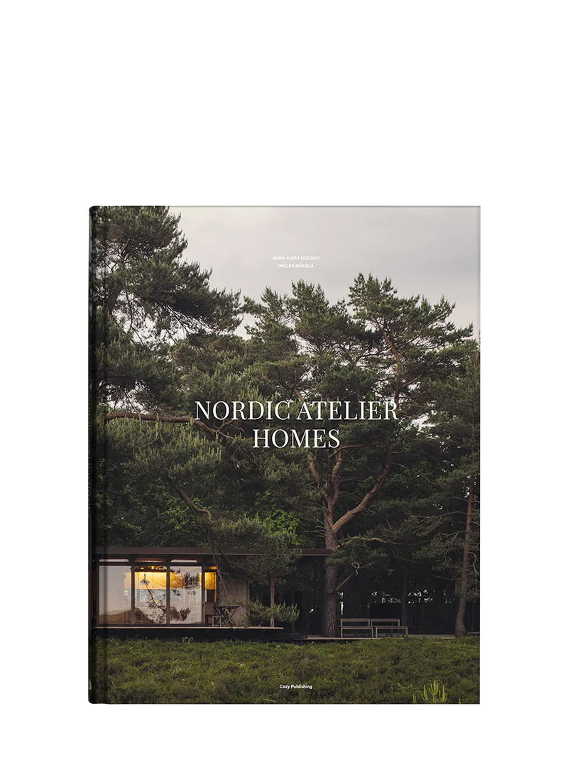Book cover titled 'Nordic Atelier Homes' featuring a modern sleek house surrounded by pine trees by Anna-Kaisa Huusko and Niclas Mäkelä for Cozy Publishing