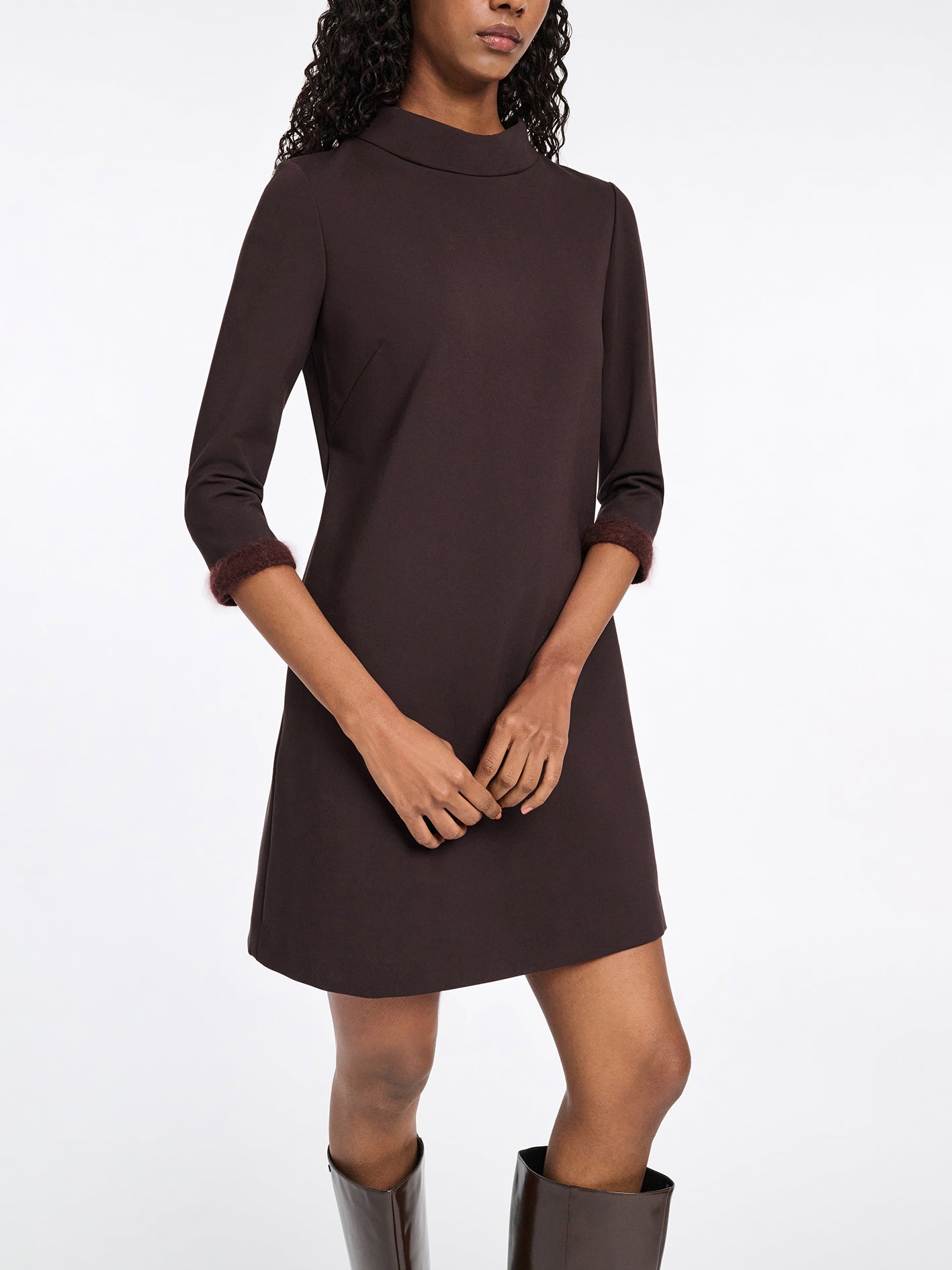 Woman wearing a brown dress with long sleeves on a white background