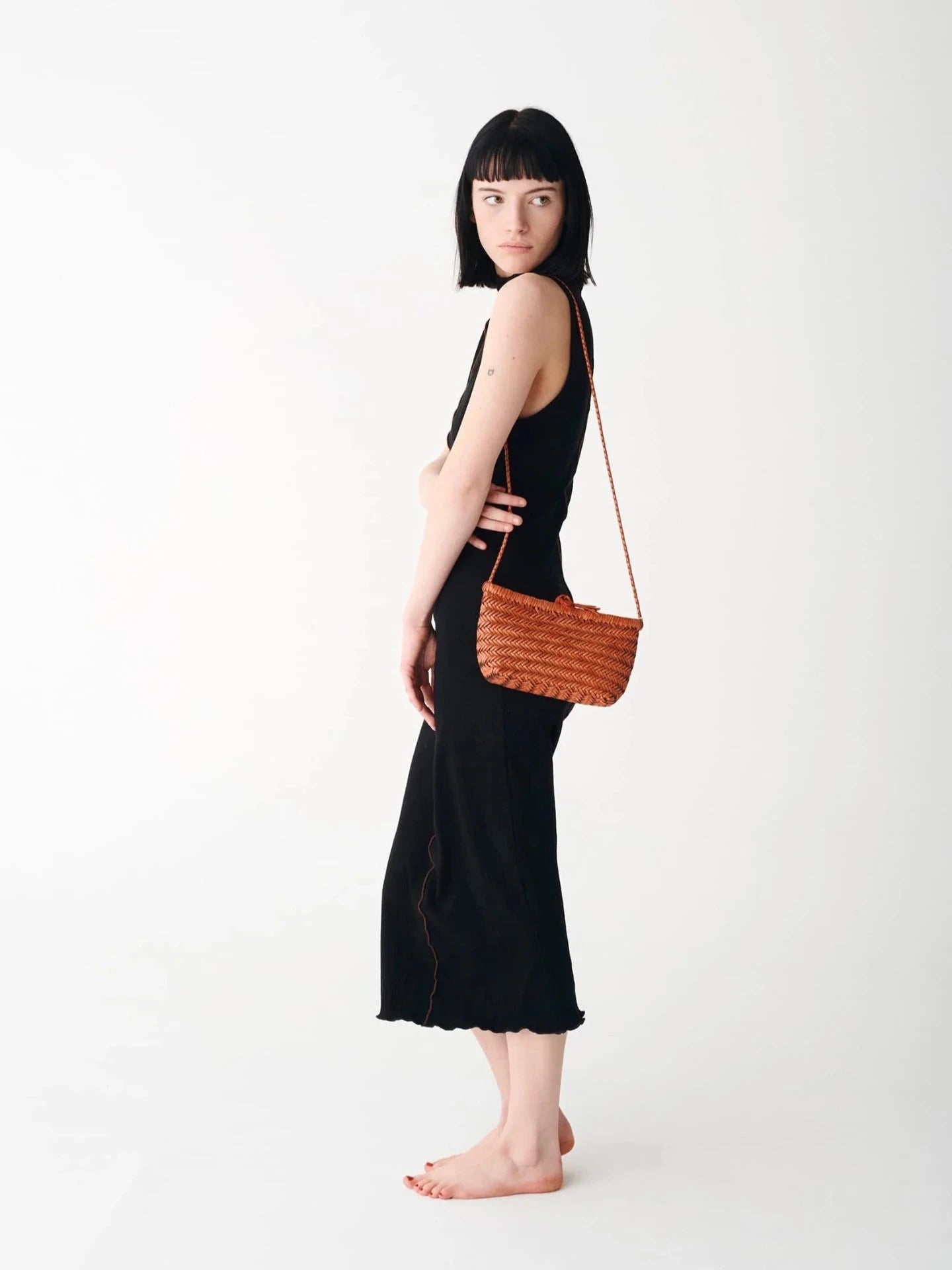 Woman holding a brown woven handbag against a white background