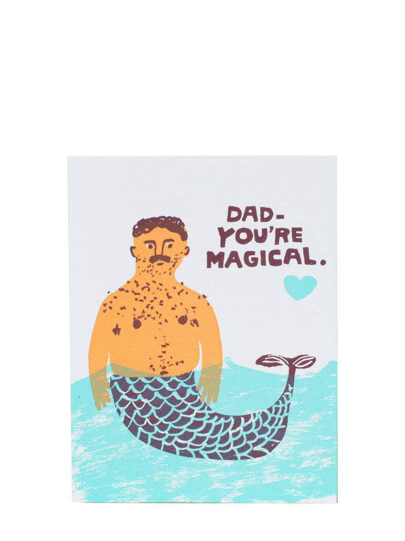A rectangular greeting card featuring a humorous illustration of a man with a mustache and a mermaid tail in water, with the text 'DAD - YOU'RE MAGICAL.' and a small heart on a white background.