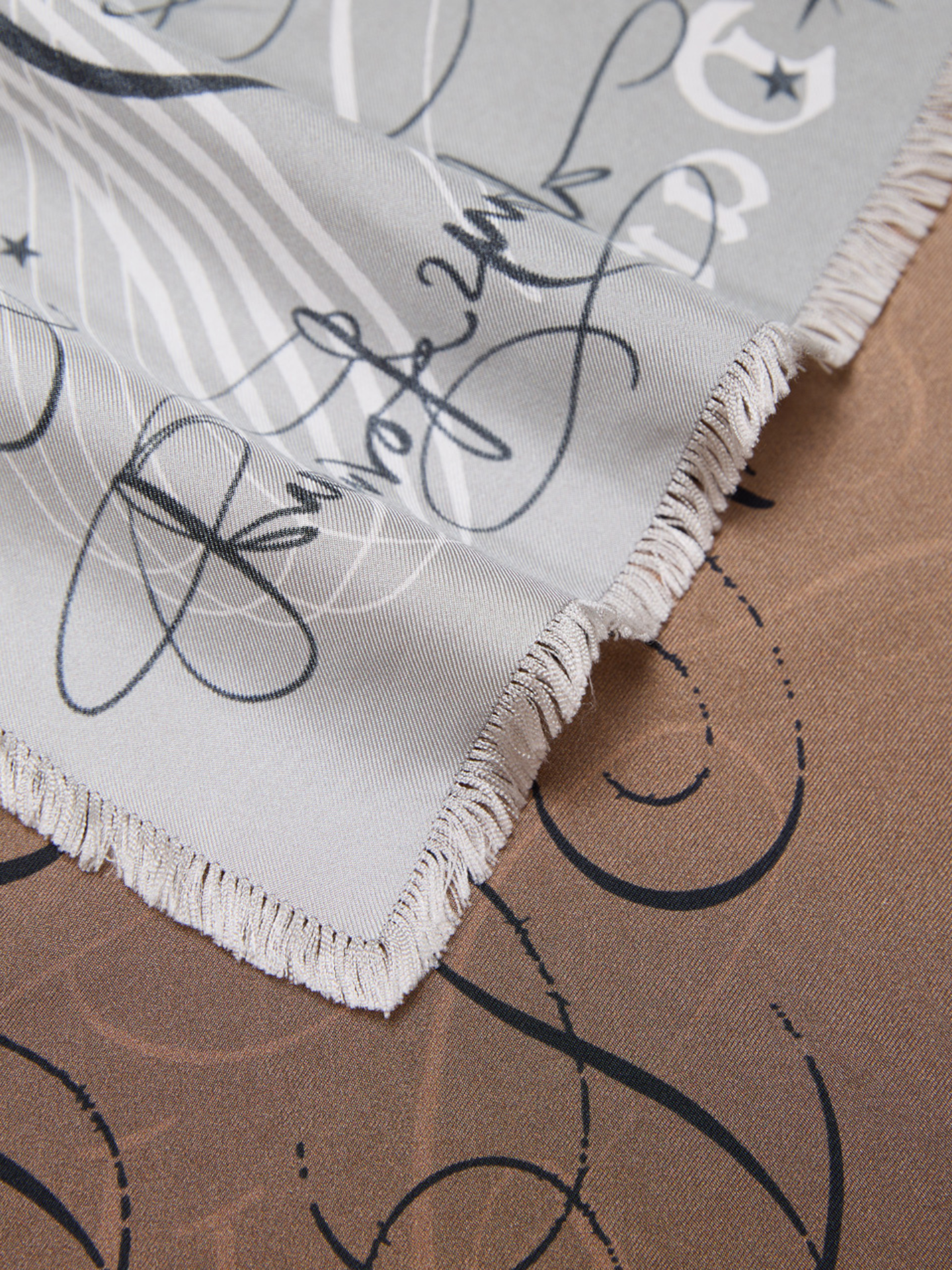 Close-up of a silk scarf with black script and white border on a brown background