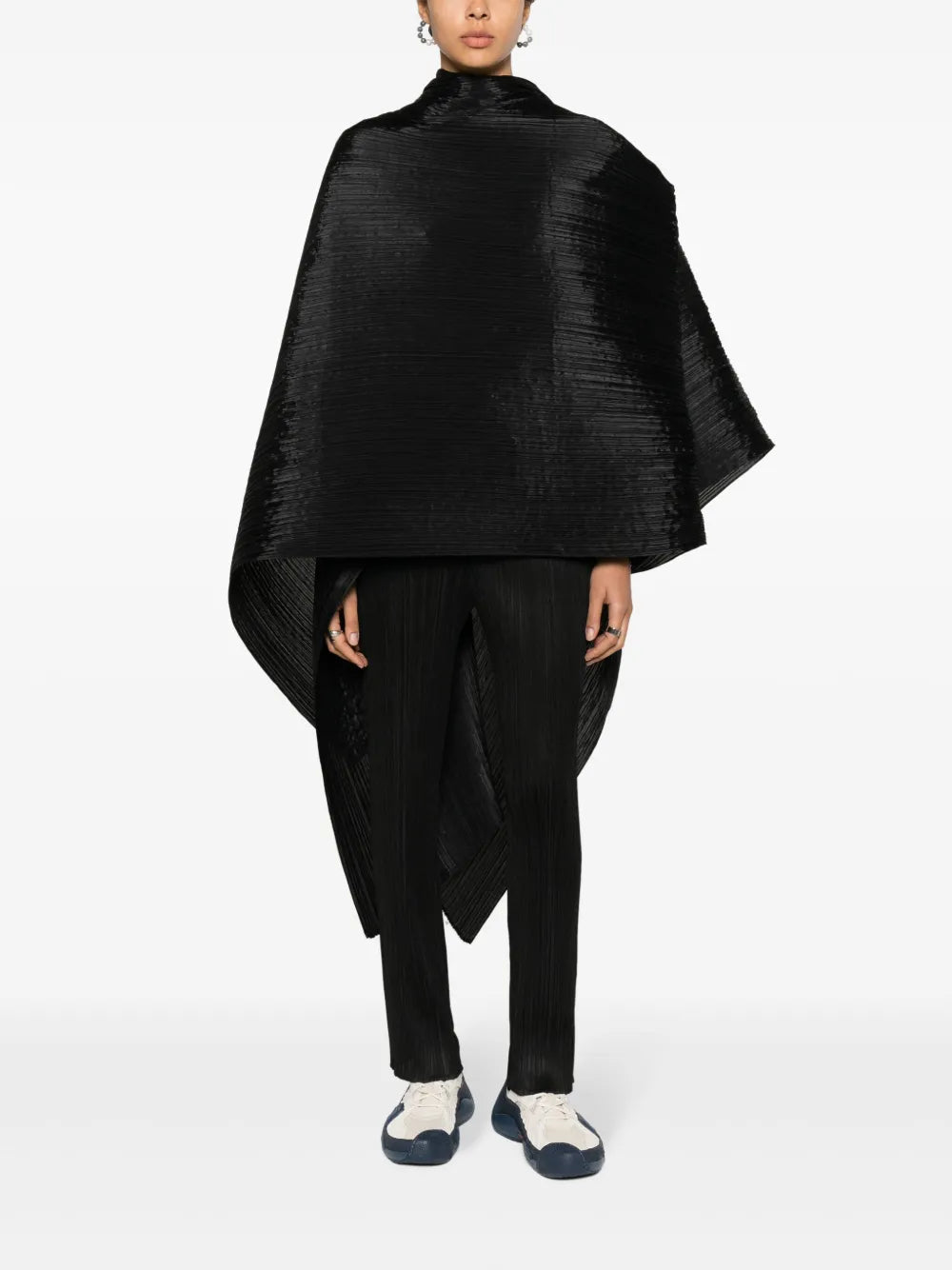 Person wearing a black poncho and pants on a white background