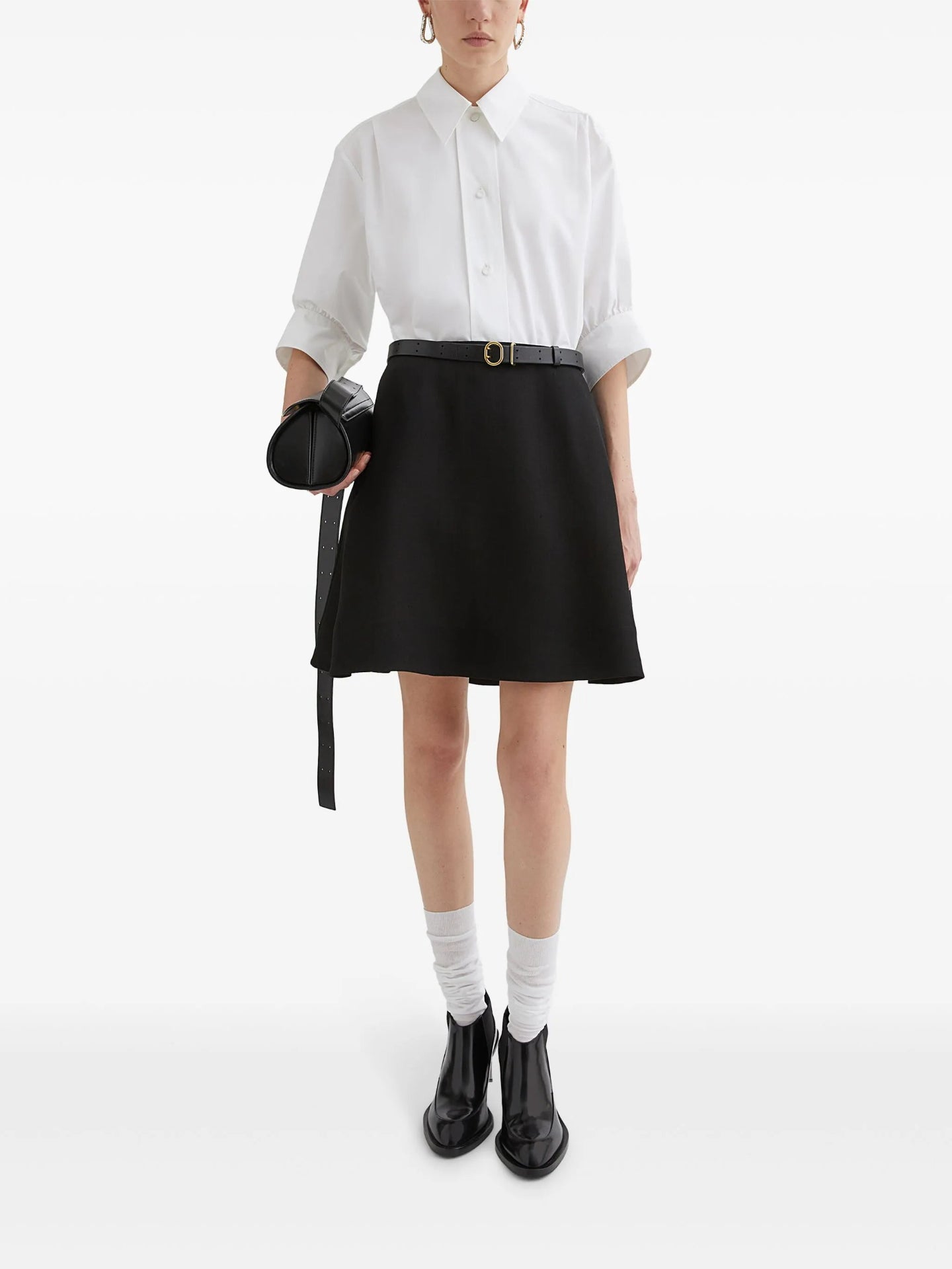 Person wearing a white shirt, black skirt, and black shoes on a white background