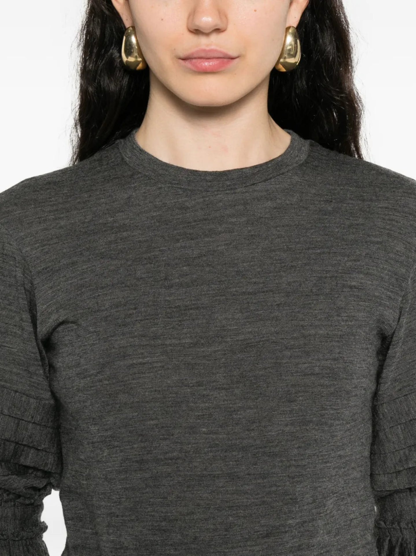 Person wearing a dark gray long-sleeve top with a plain background