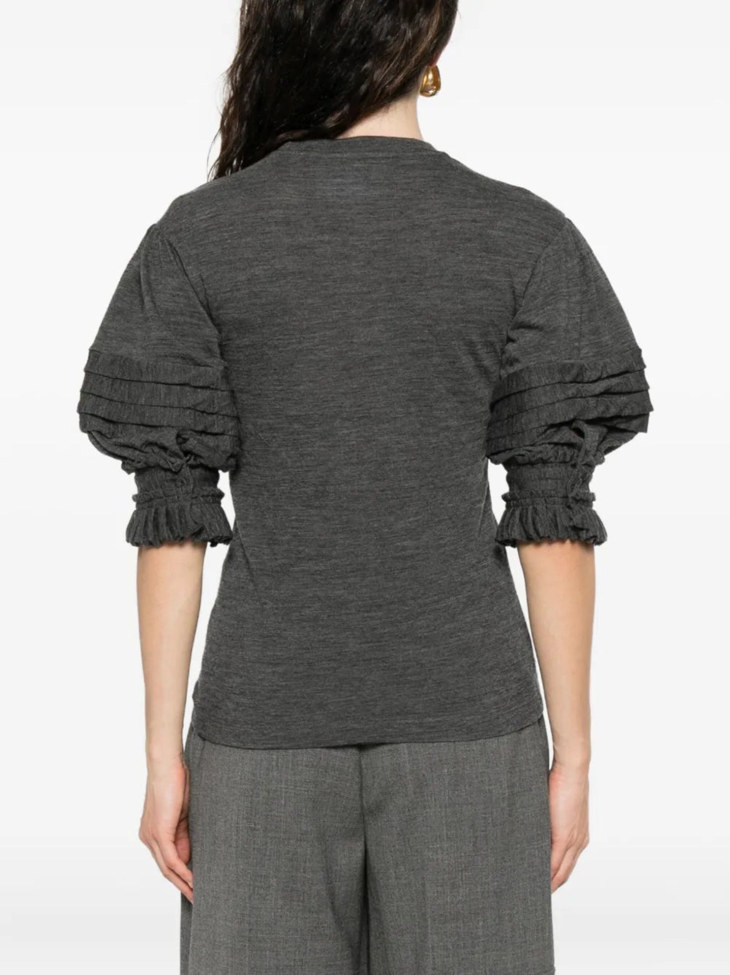 Person wearing a dark gray long-sleeve top with a plain background