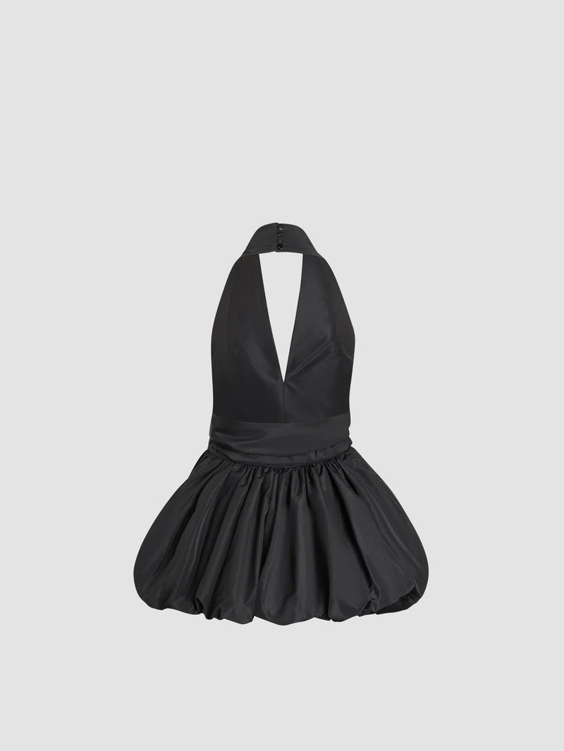 Black halter dress with a pleated skirt on a light gray background
