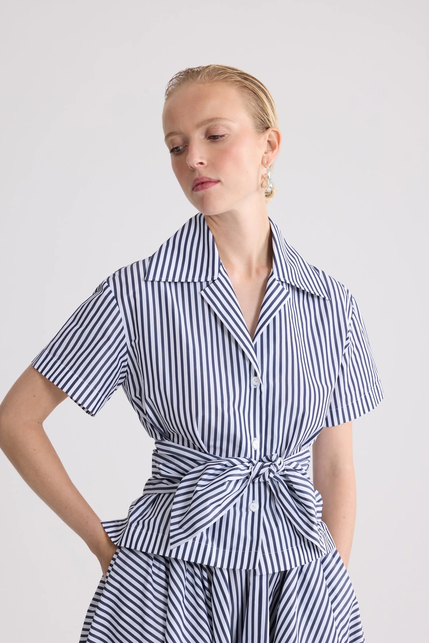 Woman wearing a blue and white striped dress against a plain background