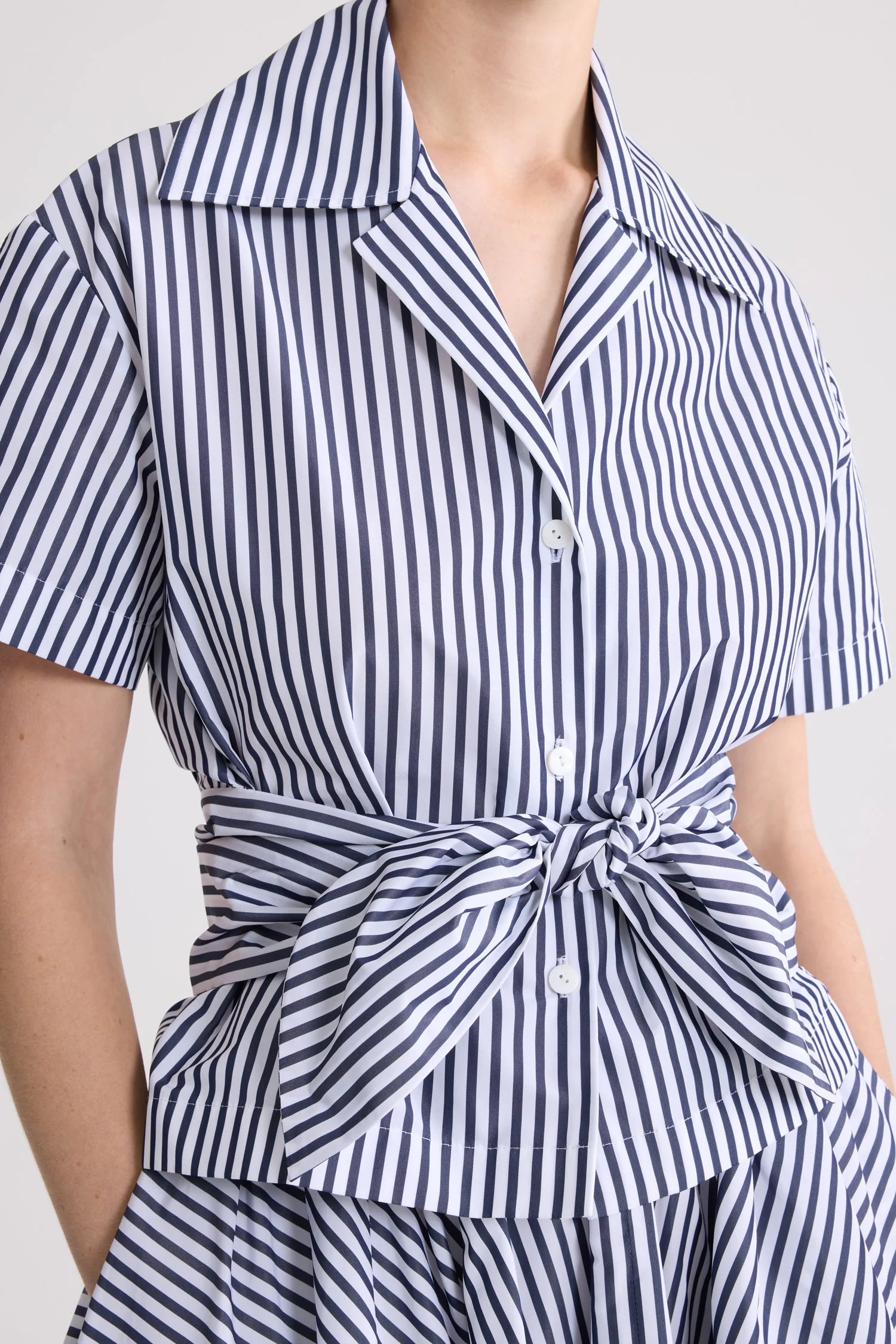 Navy and white striped dress with a tie waist on a plain background