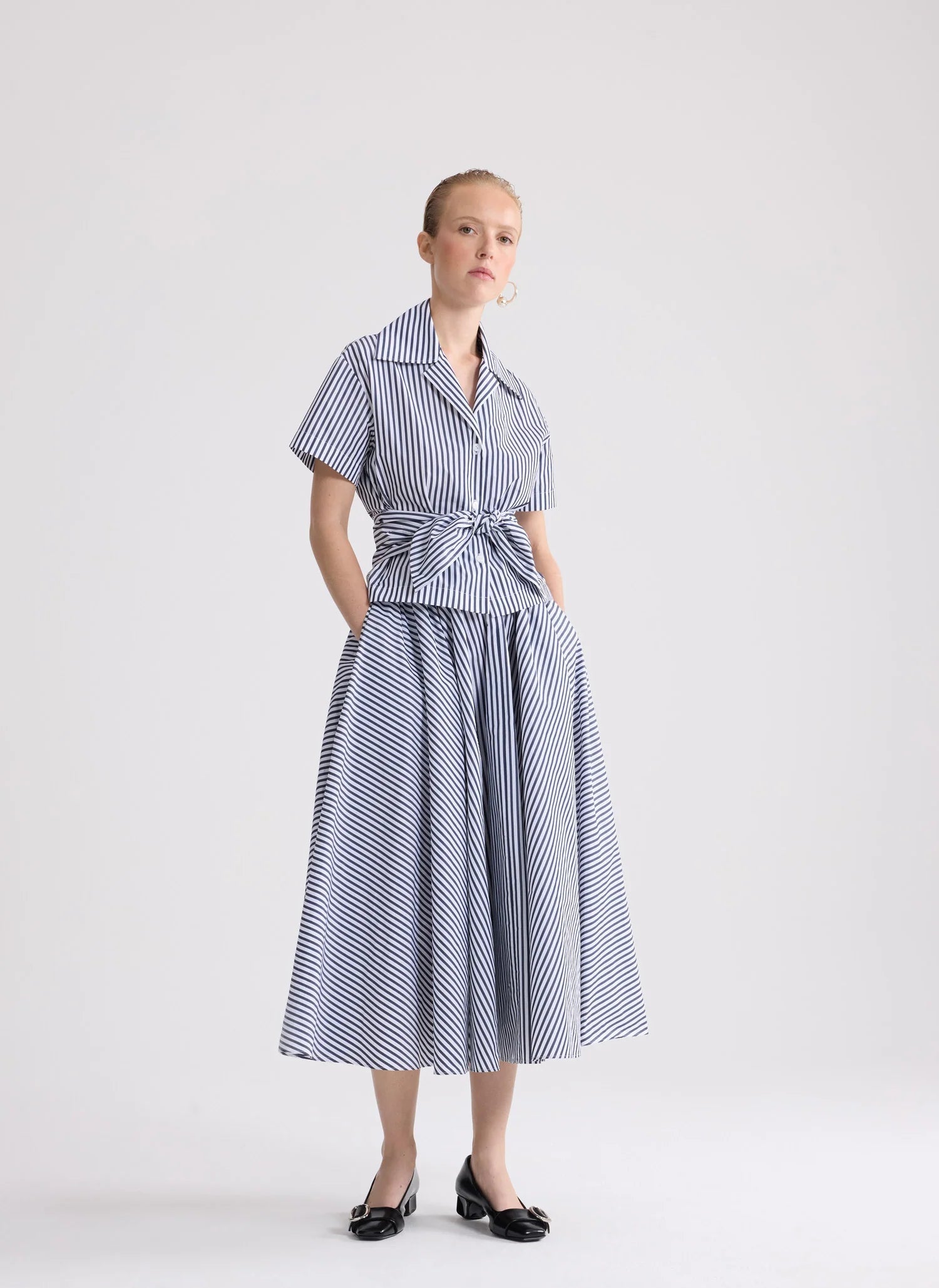 Woman wearing a blue and white striped dress on a white background