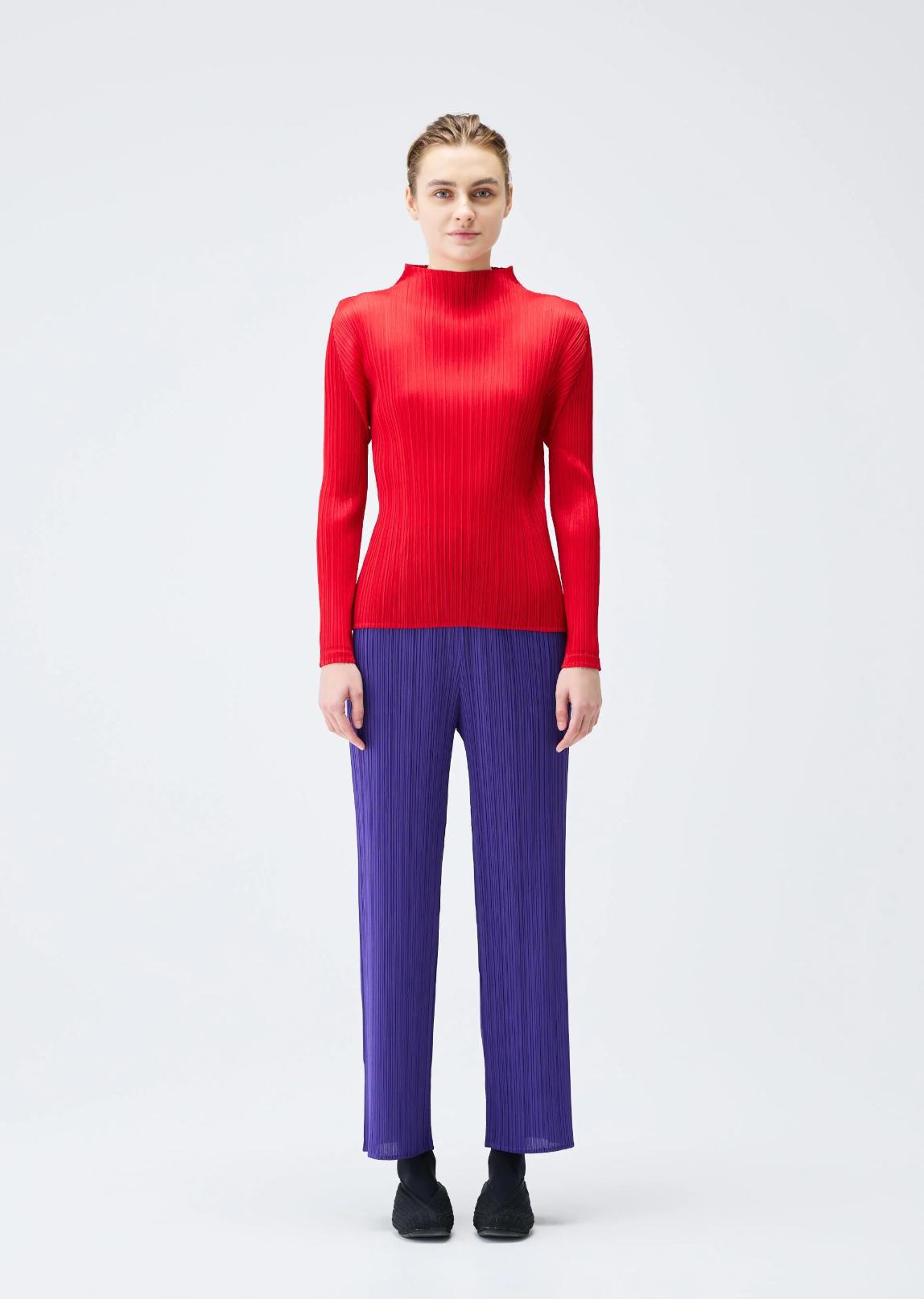 Person wearing a red sweater and purple pants on a white background